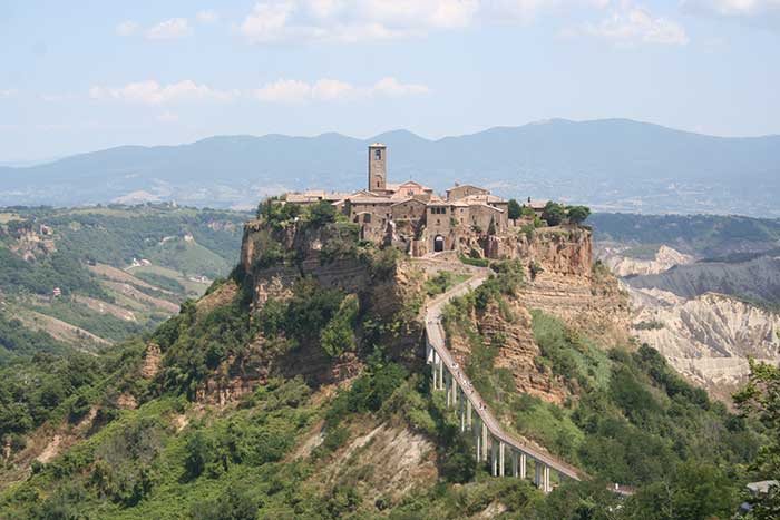Civita di Bagnoregio, is noted for its striking position atop a plateau of friable volcanic tuff overlooking the Tiber river valley, in constant danger of destruction as its edges fall off, leaving the buildings built on the plateau to crumble.